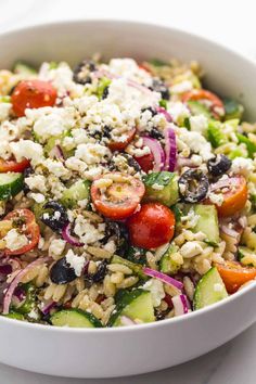 a salad with cucumbers, tomatoes, onions and feta cheese in a white bowl