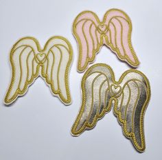 three angel wings with gold and pink trims on white background, set of 3