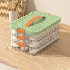 a green and white container sitting on top of a wooden table next to utensils