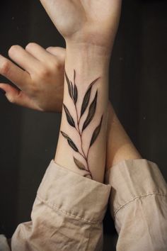 a woman's wrist tattoo with leaves on it