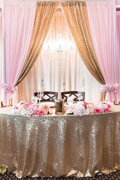 a table with pink flowers and gold sequins is set up for a wedding reception