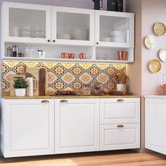 a kitchen with white cupboards and gold accents on the backsplash is shown