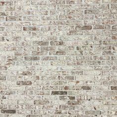 an old brick wall with white and brown paint