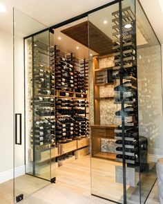 a room filled with lots of bottles of wine in glass walls next to a wooden floor