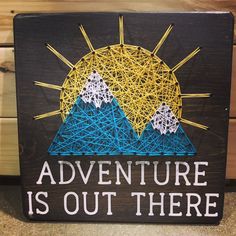 a string art sign with the words adventure is out there in front of some mountains