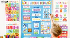 a young boy standing in front of a bulletin board with calendars and markers on it