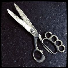 a pair of scissors sitting on top of a black table next to a pair of paw prints