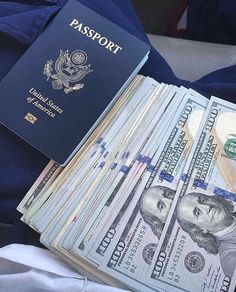 a passport sitting on top of a pile of money next to a blue bag filled with cash