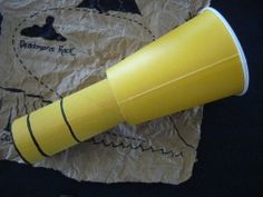 a yellow plastic cup sitting on top of a piece of paper