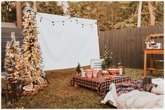 a picnic table is set up outside in the yard with christmas trees and presents on it