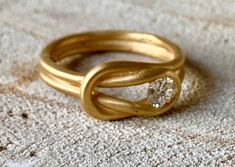 two gold rings sitting on top of each other with a diamond in the middle,