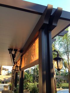 an outdoor covered patio area with lights on the side and trees in the back ground