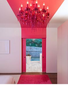 a chandelier hanging from the ceiling in a room with pink walls and doors