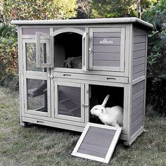 an outdoor rabbit hutch in the grass with its door open to let it inside