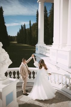 a bride and groom are dancing on the balcony