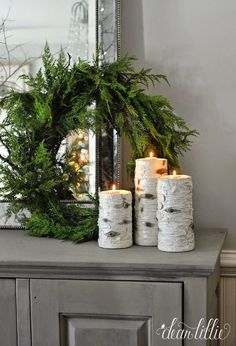 some candles are sitting on top of a table with a wreath in front of it