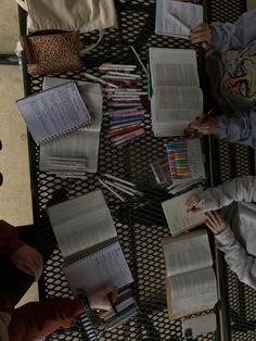 two people sitting at a table with open books