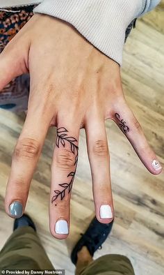 a woman's hand with a tattoo on it and two fingers in the shape of leaves