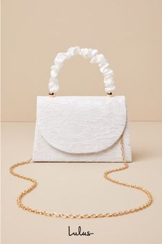 There is no easier way to elevate your springtime looks than with the Lulus Exceptional Class Ivory Lace Ruched Handle Mini Handbag! Chic floral lace (atop woven satin) shapes this cute mini bag that boasts a structured silhouette, a ruched satin top handle with gold beaded accents, and a flat bottom design. The front flap features a hidden magnetic closure that opens to reveal a lined, compact interior with a sidewall pocket. Attach the removable gold chain strap when you want a crossbody look! Elegant Beige Evening Bag For Spring, Spring Party Bags With Pearl Handle, Chic Spring Fabric Bag, Spring Evening Bag With Pearl Handle, White Elegant Evening Bag For Summer, Elegant White Evening Bag For Summer, Cream Bags For Spring Party, Elegant White Evening Bag For Spring, White Wedding Bags For Spring