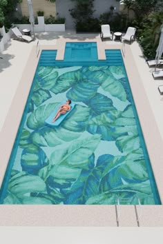 an aerial view of a pool with a person in the water and chairs around it