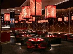 a restaurant with round tables and red lights hanging from the ceiling above them, along with circular chandeliers