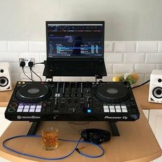 a laptop computer sitting on top of a dj's desk next to headphones