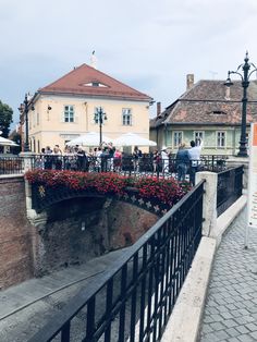 people are standing on the bridge and some have umbrellas over them while others walk by