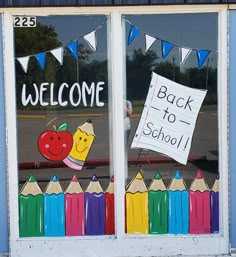 the back to school window is decorated with chalk and crayon pencils as well as a welcome sign