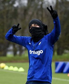 a soccer player wearing a black mask and holding his hands up in the air