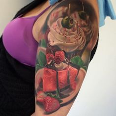 a woman with a tattoo on her arm holding a cupcake and some strawberries