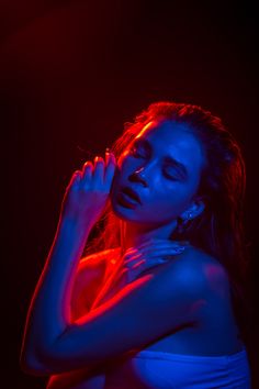 a woman in blue and red light posing for the camera with her hands on her chest