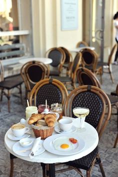 breakfast is served on an outdoor table in the middle of a courtyard cafe, with people walking by