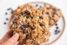 a person holding up a cookie with chocolate chips on it