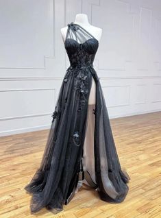 Slip into elegance with this stunning black prom dress, crafted to captivate and enchant. The dress boasts a unique one-shoulder neckline, elegantly draped with soft tulle and adorned with intricate floral appliques, offering a look that is both modern and timeless. The bodice is meticulously tailored to provide a flattering fit, cinching at the waist to highlight your natural curves. The skirt flows into a magnificent A-line silhouette, made from layers of delicate tulle that drape beautifully to the floor. The black color adds a sense of mystery and sophistication, making it an ideal choice for any formal event. The back of the dress features a seamless zipper closure for a secure and comfortable fit. Perfect for prom, weddings, or any special occasion, this dress will make you feel like Black Lace Prom Dress, Prom Outfit, Formal Dresses Graduation, Gorgeous Prom Dresses, 파티 드레스, Graduation Dresses, Prom Dress Inspiration, Black Prom, Long Prom Dresses