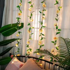 a bed with flowers and lights hanging from the ceiling next to a curtained window