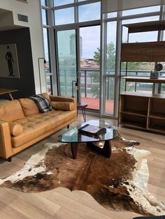 a living room with two couches and a table in front of glass doors that look out onto the city