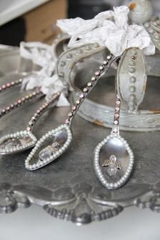 three silver spoons with beaded designs on them sitting on a tray next to a white flower