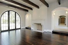 an empty living room with wood floors and large arched windows in the middle of it