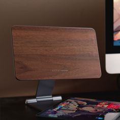 a wooden desk top sitting next to a computer monitor on a black table with a book