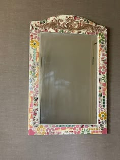 the mirror is decorated with colorful flowers and leaves on it's sides, as well as an ornate frame