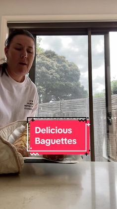 a woman sitting at a table in front of a window with the words delicious baguettes on it