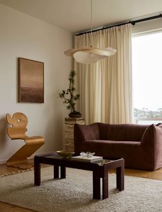 a living room with a couch, coffee table and chair in front of a window