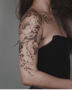 a woman's shoulder with flowers and leaves on her arm, in black and white