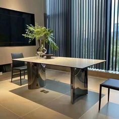 a dining room table with two chairs and a vase on it in front of a flat screen tv