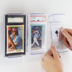 a person is holding two baseball cards on the wall and one has an iphone in it