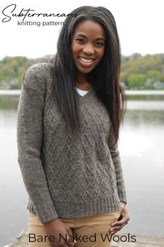 a woman standing next to a body of water wearing a sweater and tan pants with the words bare naked wools on it