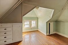 an empty room with hard wood floors and white cabinets in the corner on the far wall