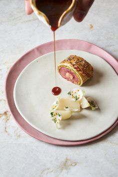 someone is pouring sauce on a piece of meat with cheese and crackers in the shape of a heart