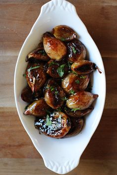 a white bowl filled with cooked food on top of a wooden table