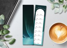 a cup of coffee next to a bookmark with a heart on it and some leaves